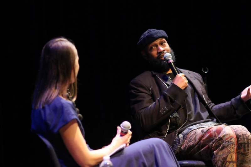 a man and woman sitting in chairs with microphones