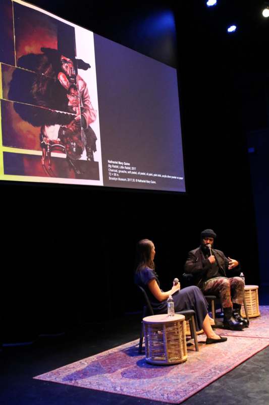 a man and woman sitting in chairs on a stage