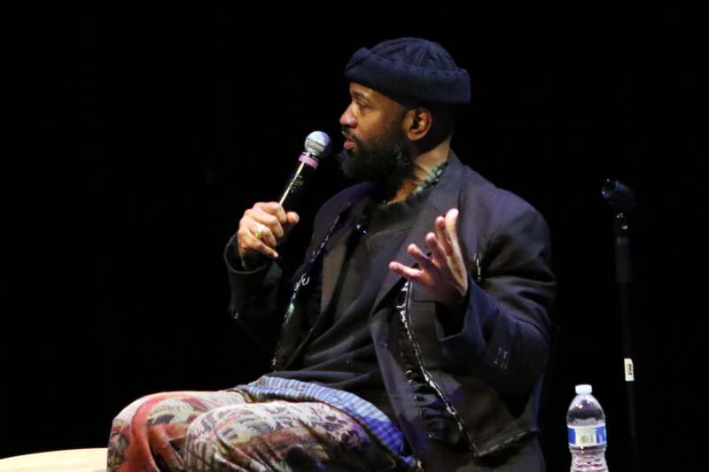 a man sitting on a stage holding a microphone