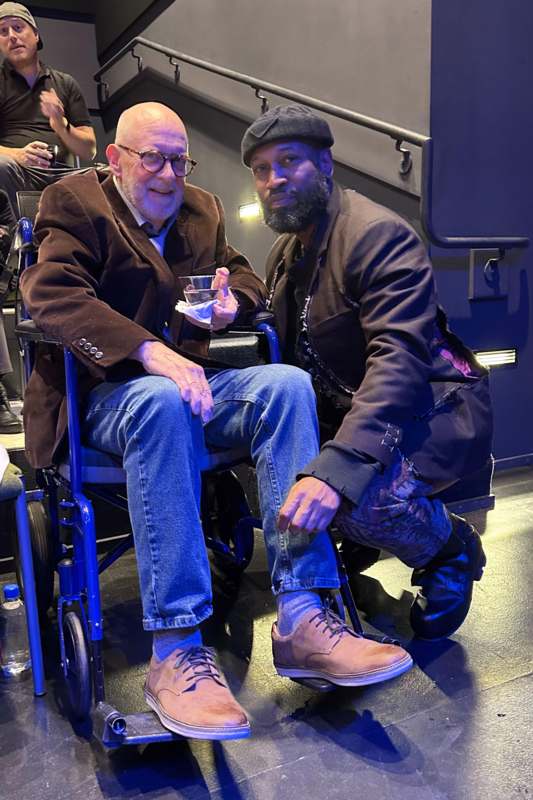 two men sitting in a wheelchair