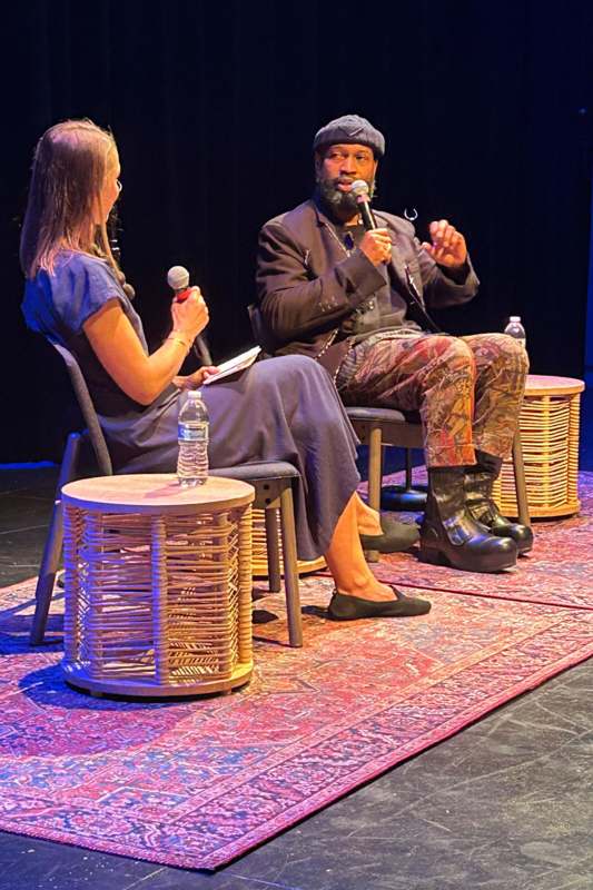 a man and woman sitting on a stage with microphones