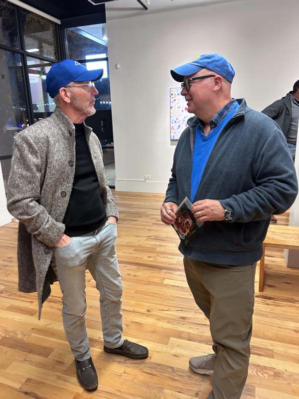 two men in a room with art