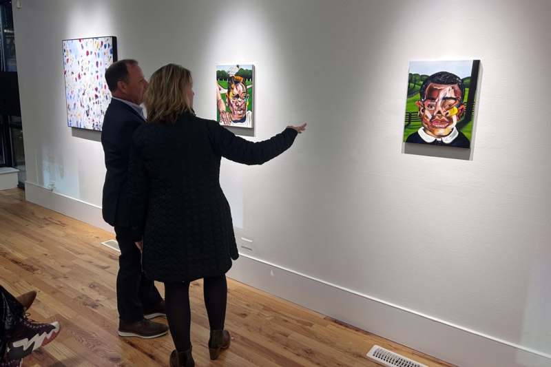 a man and woman looking at paintings on a wall