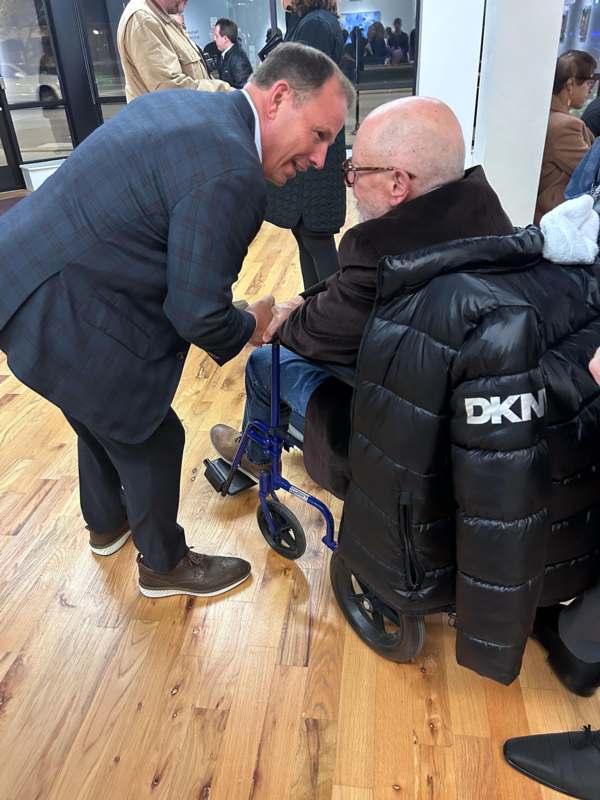 a man in a suit pushing a man in a wheelchair