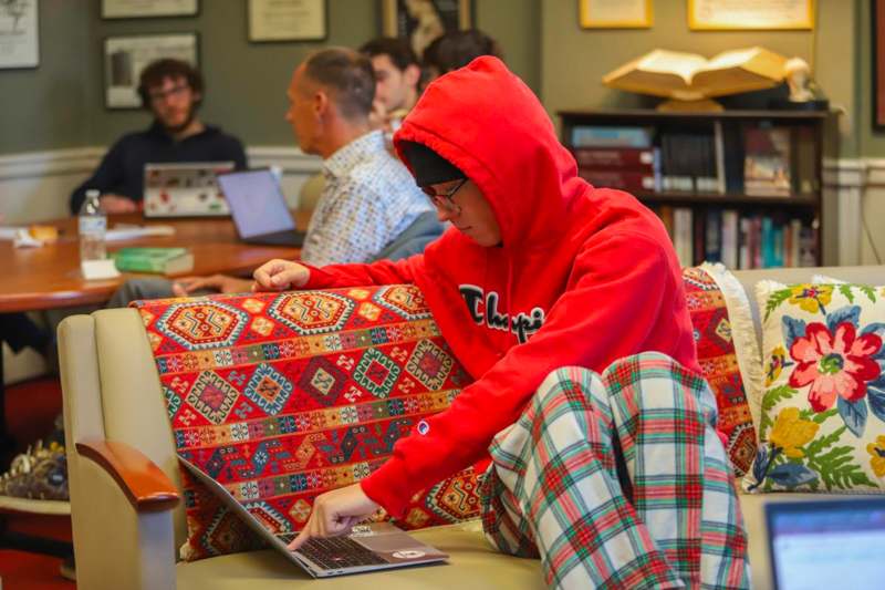 a person in a red hoodie using a laptop