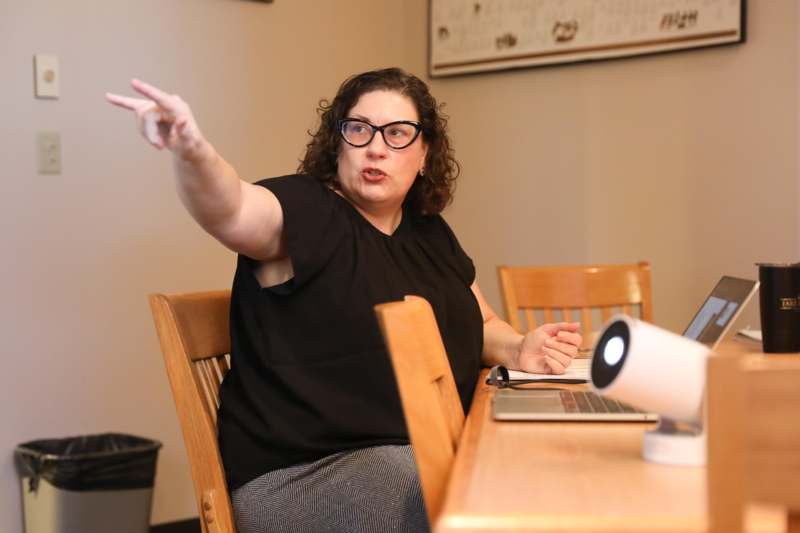 a woman sitting at a table pointing at something