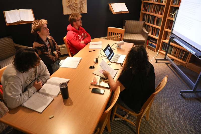 a group of people sitting around a table with books