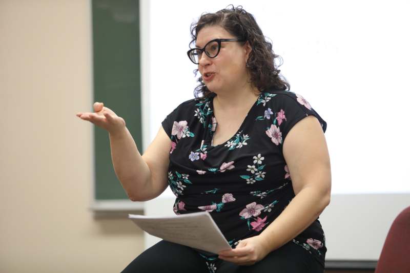 a woman sitting in a chair holding a piece of paper