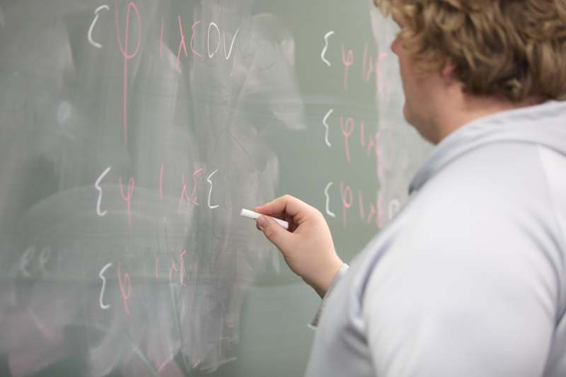 a man writing on a chalkboard