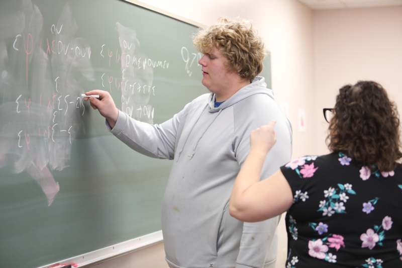 a man writing on a chalkboard