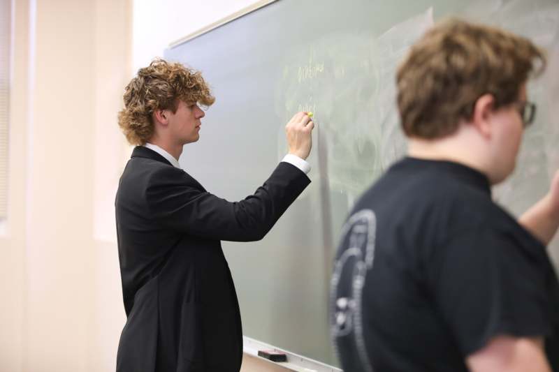 a man writing on a chalkboard