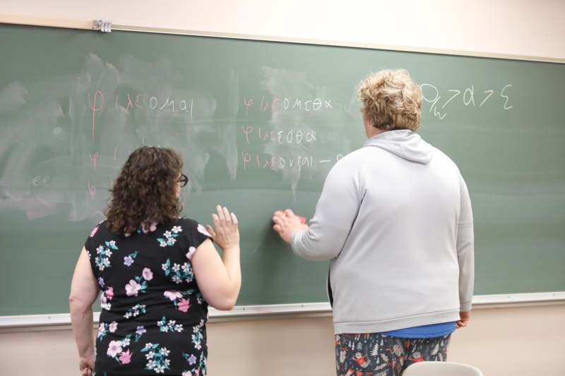 a woman and a woman standing in front of a chalkboard