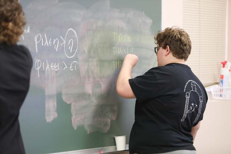 a person writing on a chalkboard