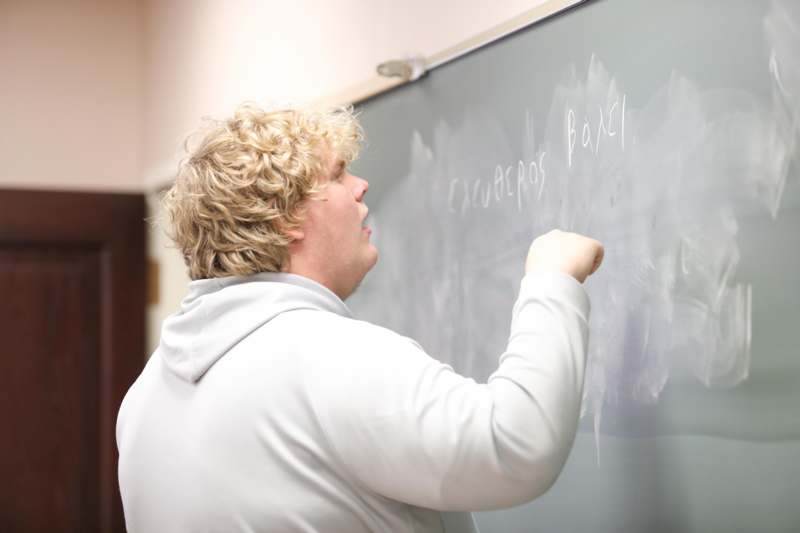 a man writing on a chalkboard