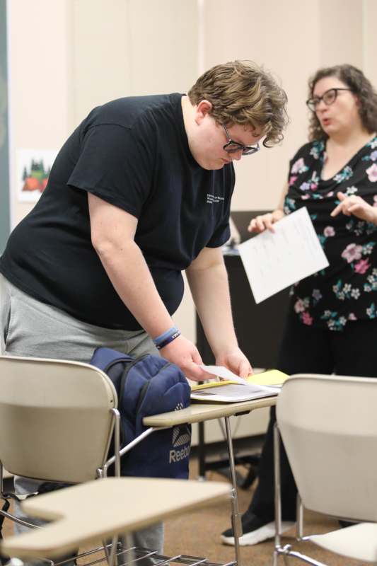 a woman standing next to a man looking at a piece of paper