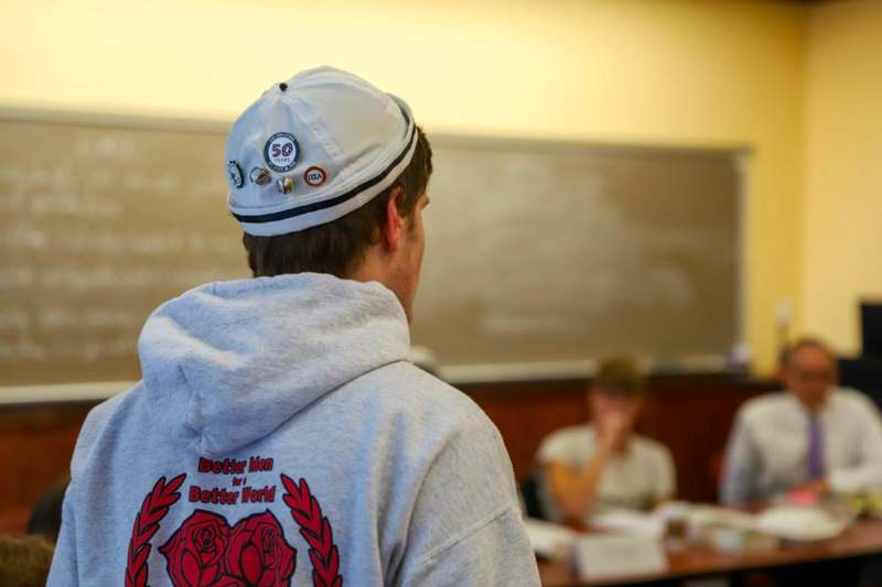 a man wearing a hat with pins on his back