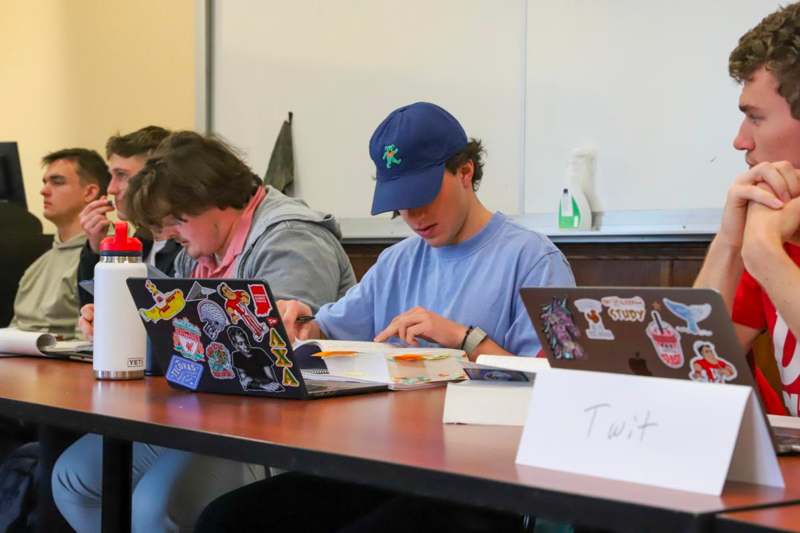 a group of people sitting at a table with laptops