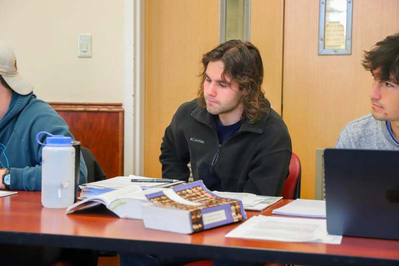 a man sitting at a table with books on it