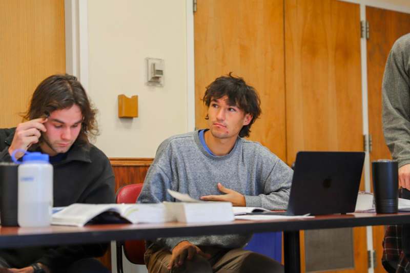 a group of men sitting at a table with a laptop