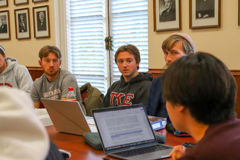 a group of people sitting around a table with laptops