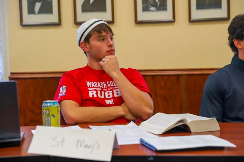 a man sitting at a table with his hand on his chin