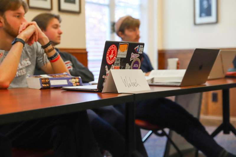 a group of people sitting at a table with laptops