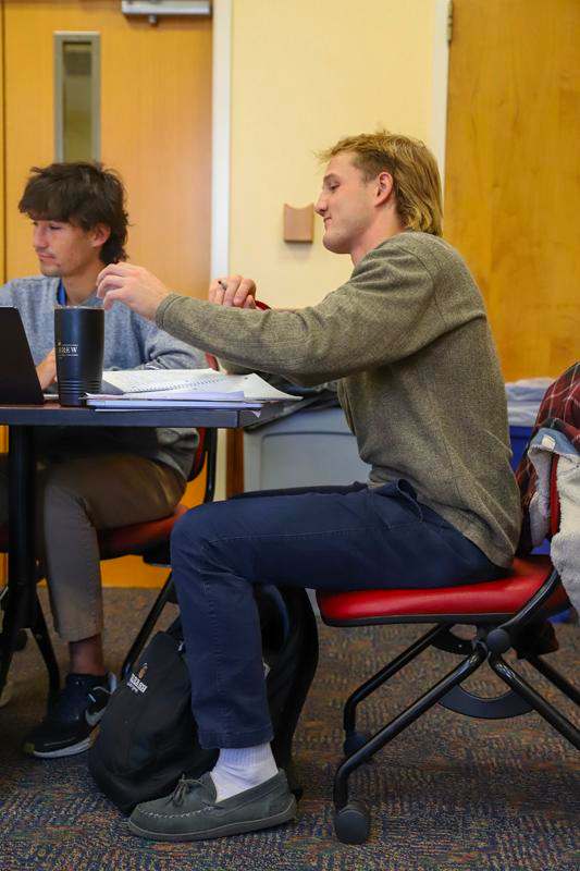 a man sitting at a table with another man in a chair