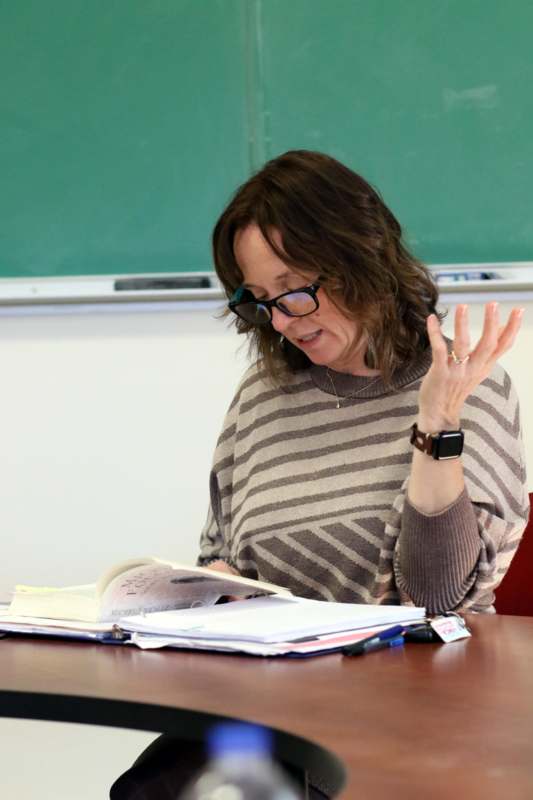 a woman sitting at a desk with her hand raised