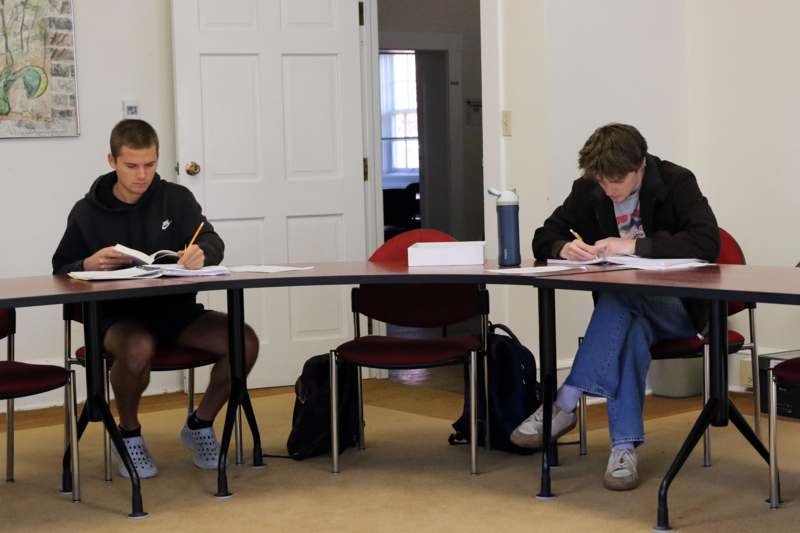 a group of people sitting at a table writing