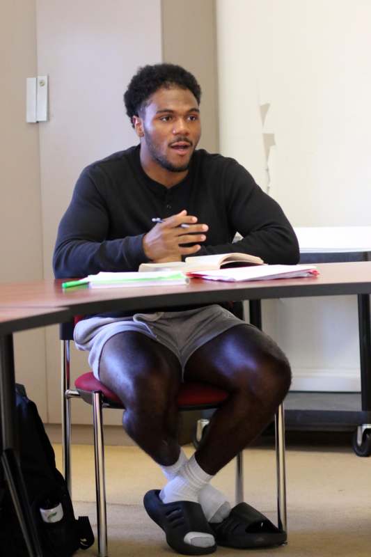 a man sitting at a table with a book and a pen