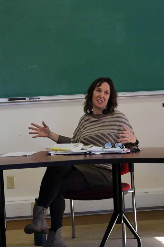 a woman sitting at a table with her hands raised