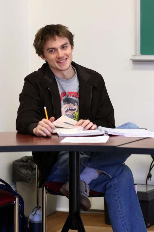 a man sitting at a table with books and pencils
