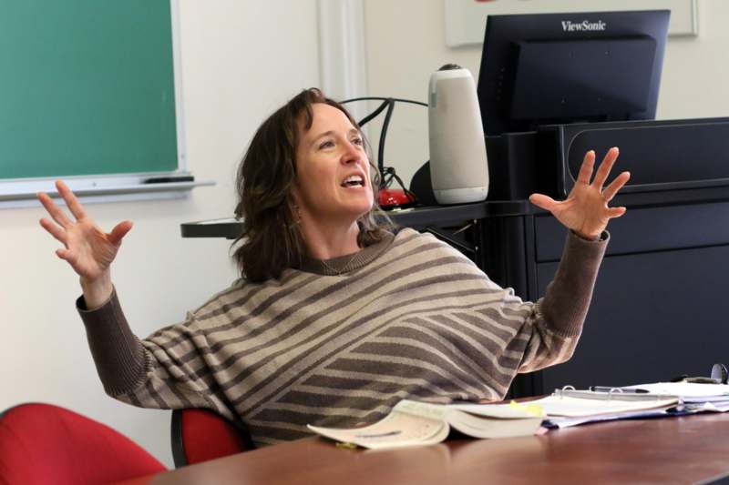 a woman sitting at a desk with her hands up