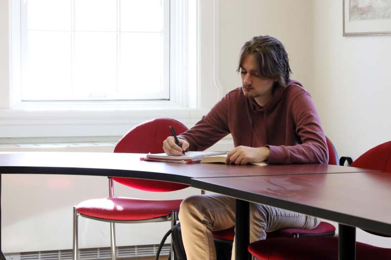 a man sitting at a table writing on a book