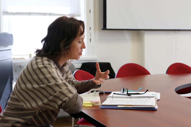 a woman sitting at a table with papers and glasses