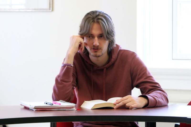 a man sitting at a table with a book and pen