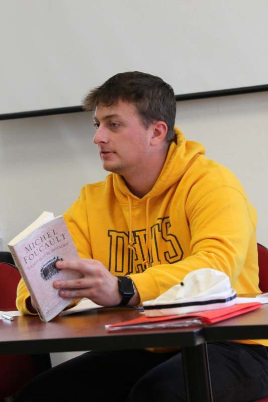 a man in a yellow sweatshirt reading a book