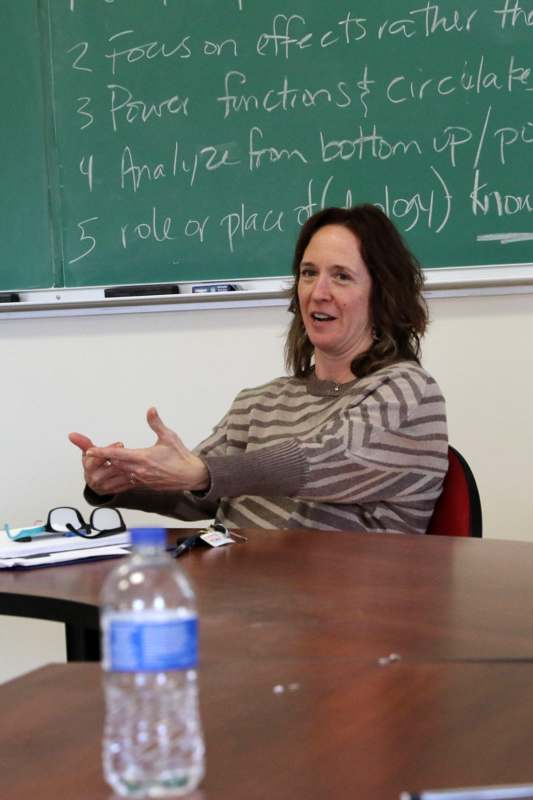 a woman sitting at a table with her hands in front of her