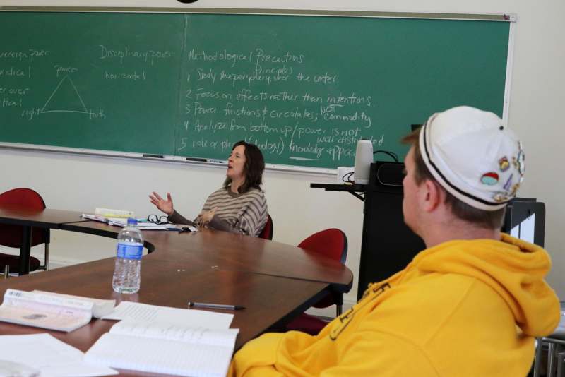 a woman sitting at a table in front of a chalkboard