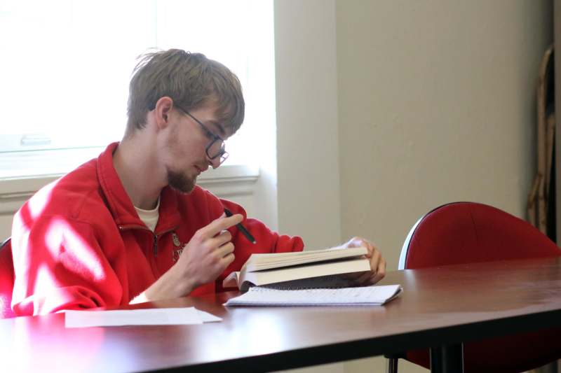 a man sitting at a table with a book and a pen