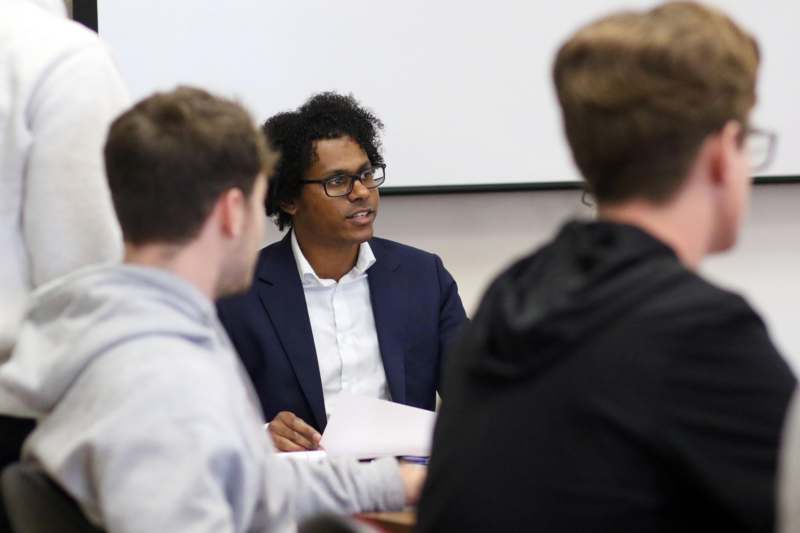 a man in a suit sitting at a table with other people