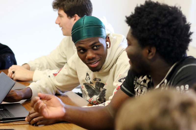 a man in a green head scarf sitting at a table