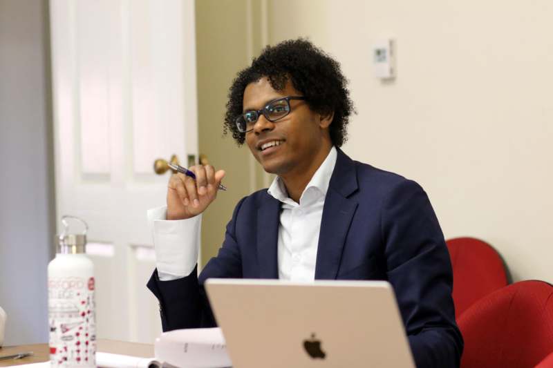 a man sitting at a desk with a laptop and a pen