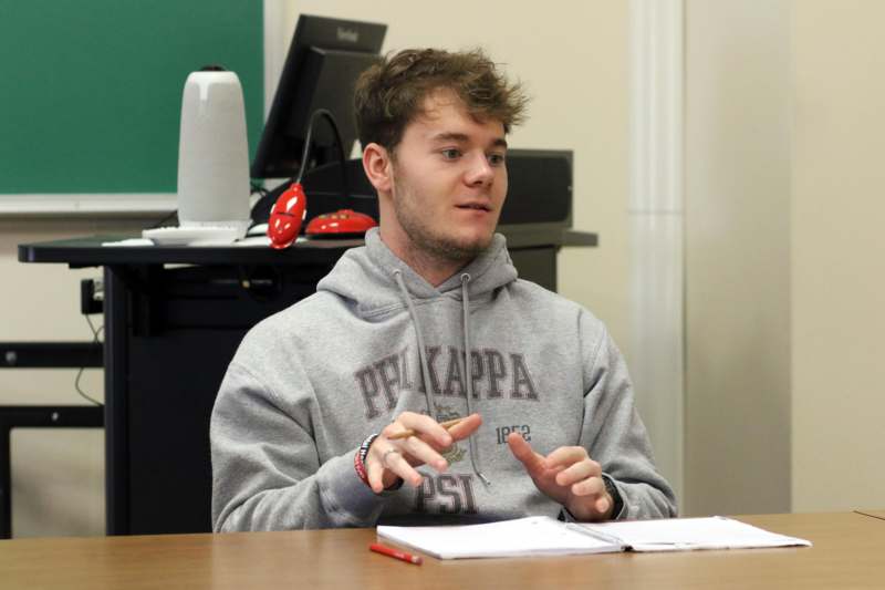 a man sitting at a table with a book and pencils