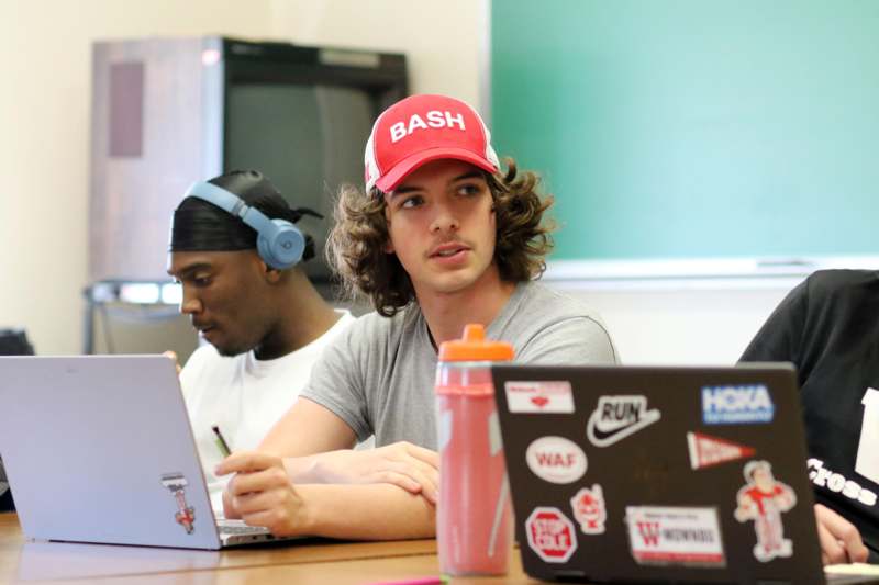 a man in a red hat sitting at a table with a laptop