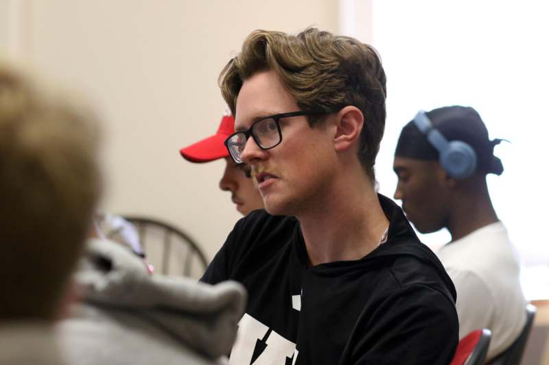 a man in glasses looking away from other people
