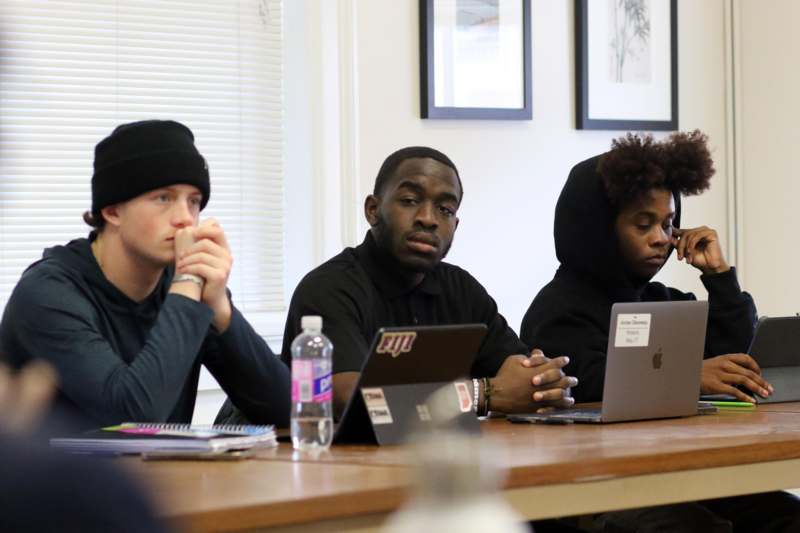 a group of people sitting at a table with laptops