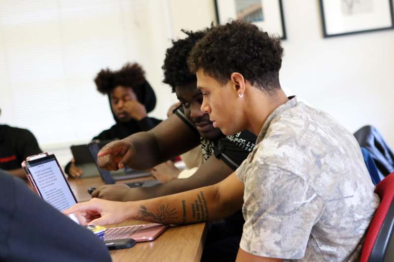 a group of people sitting at a table looking at a laptop