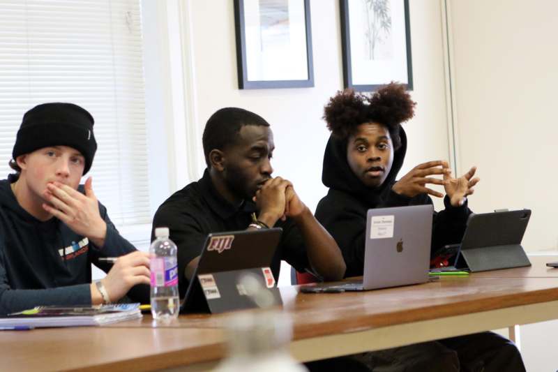 a group of people sitting at a table with laptops