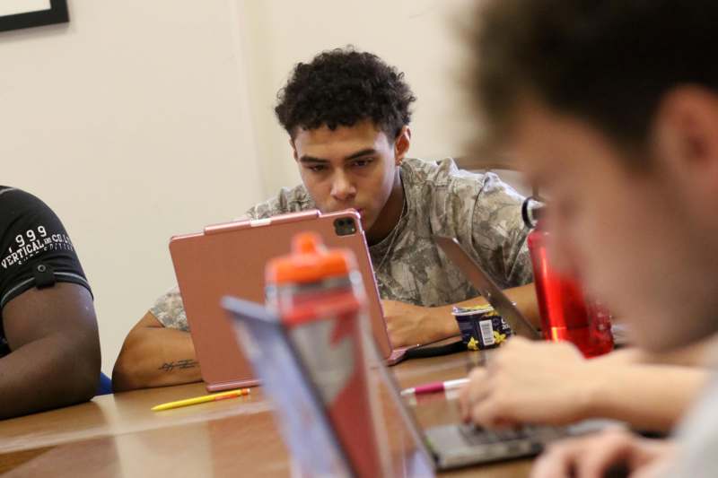 a group of people sitting at a table with laptops